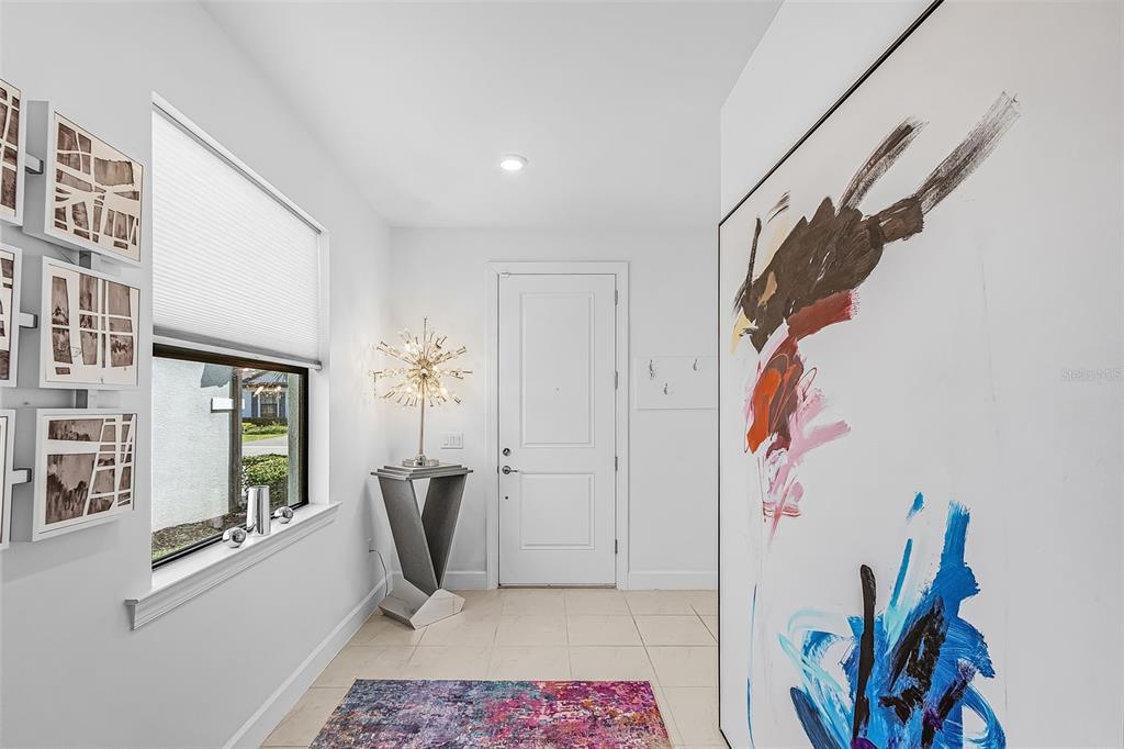 A bright entryway features white walls, tile flooring, a modern starburst lamp, and abstract art — 3990 SPOTTED EAGLE WAY, FORT MYERS, FL