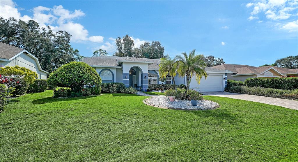 A single-story house with a white garage, arched entryway, and a landscaped front lawn — 9528 HAWKSMOOR LANE, SARASOTA, FL