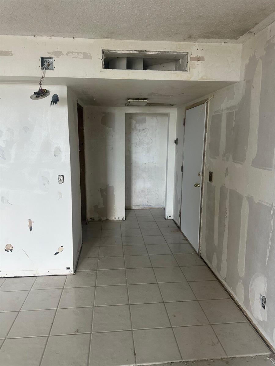 An unfinished interior hallway with tiled flooring, exposed drywall, and an open ceiling vent — 2425 Presidential Way # 1203, West Palm Beach FL 33401, WEST PALM BEACH, FL