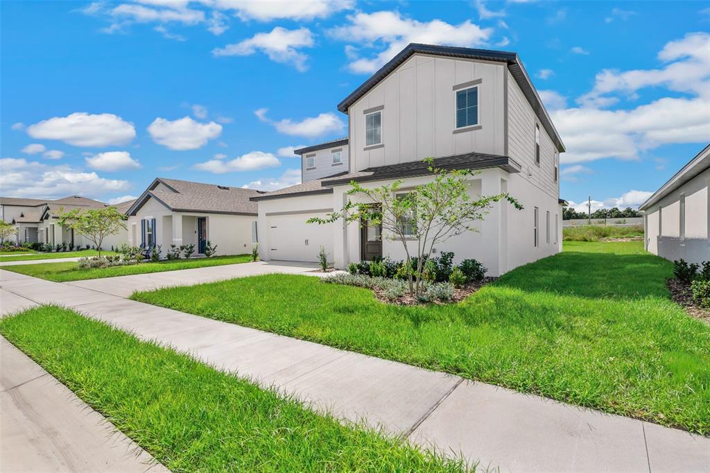 A two-story white house with a garage and a front lawn under a blue sky — 1205 WAHNETA COURT, POINCIANA, FL