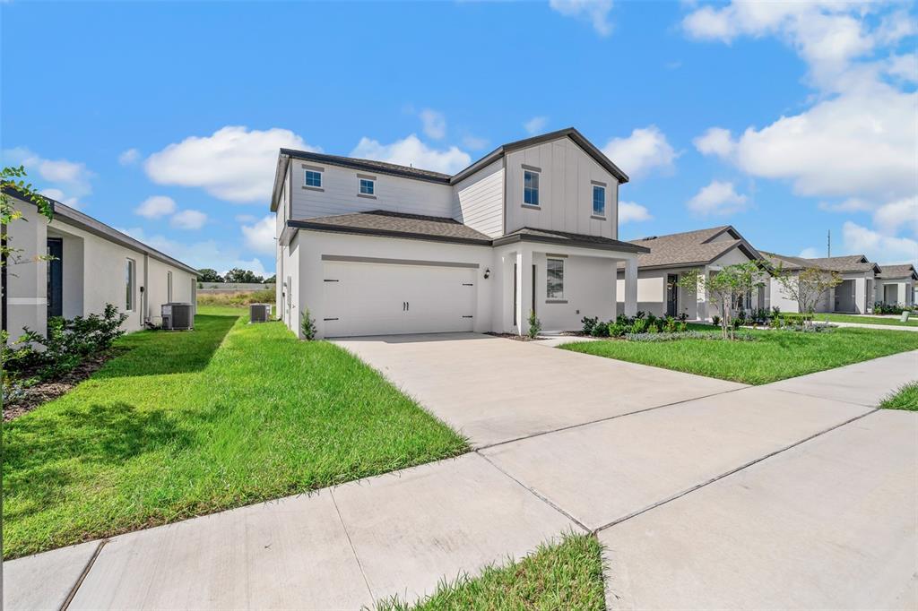 A two-story white house with a two-car garage and a concrete driveway — 1205 WAHNETA COURT, POINCIANA, FL