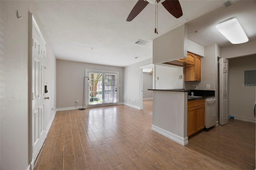 A living room with wood-look tile floors, a ceiling fan, and an adjacent kitchen area — 241 AFTON SQUARE UNIT 103, ALTAMONTE SPRINGS, FL