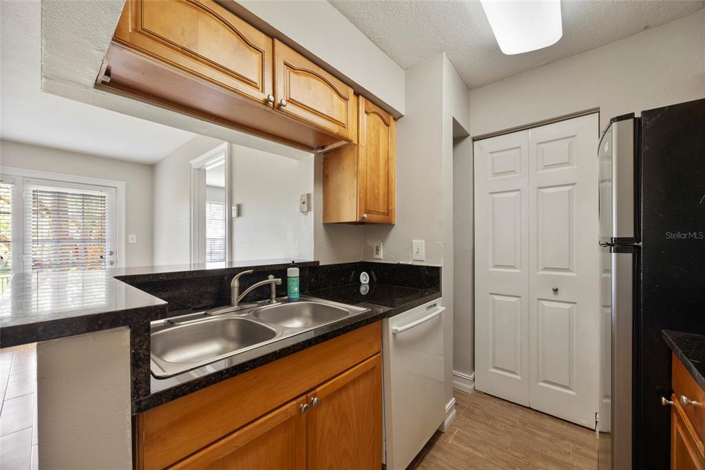 A kitchen features wood cabinets, dark granite countertops, a double sink, and a white dishwasher — 241 AFTON SQUARE UNIT 103, ALTAMONTE SPRINGS, FL