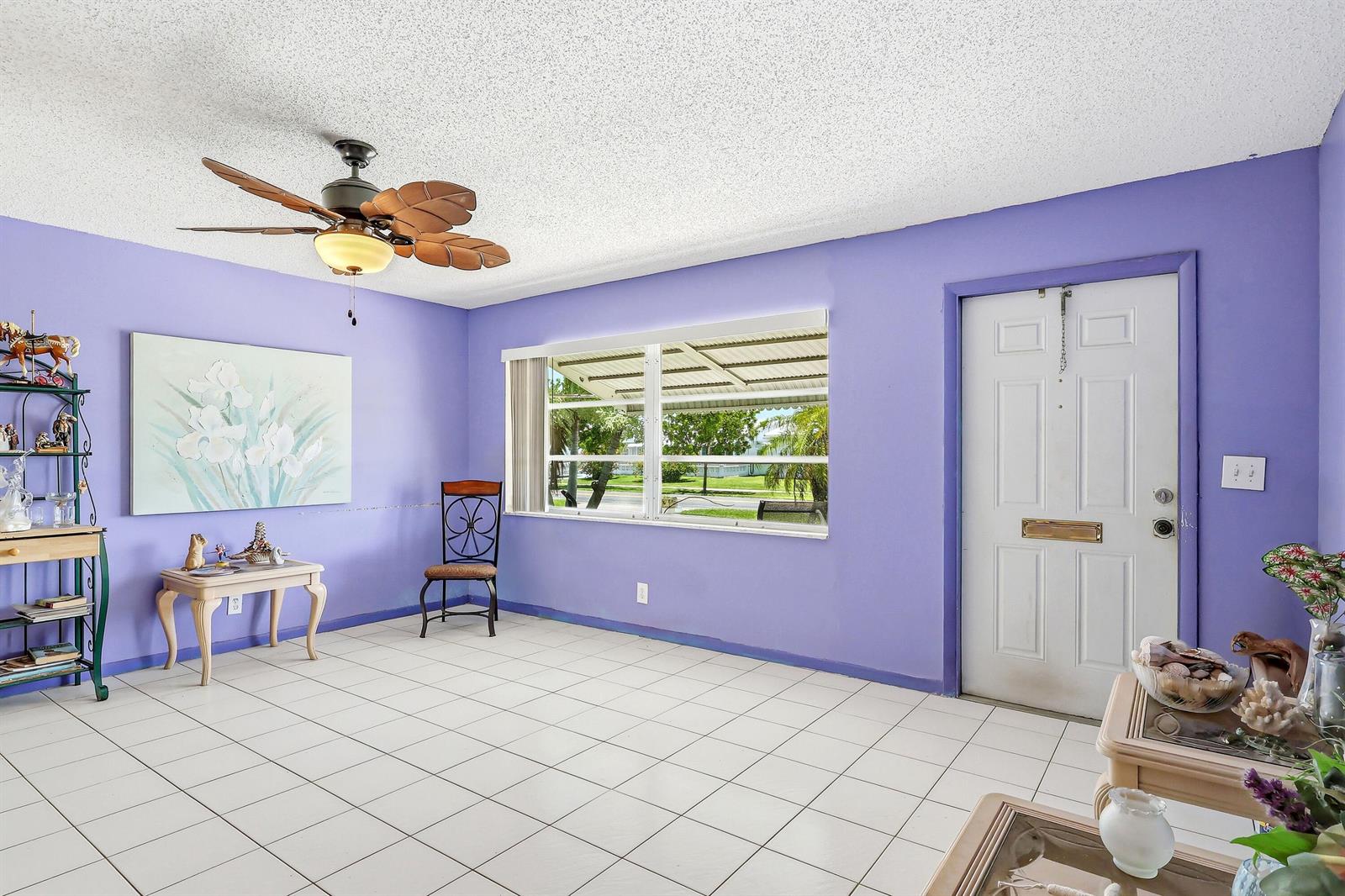 A living room with purple walls, white tile flooring, a ceiling fan, and a front door — 712 SW 18th Street, Boynton Beach FL 33426, BOYNTON BEACH, FL