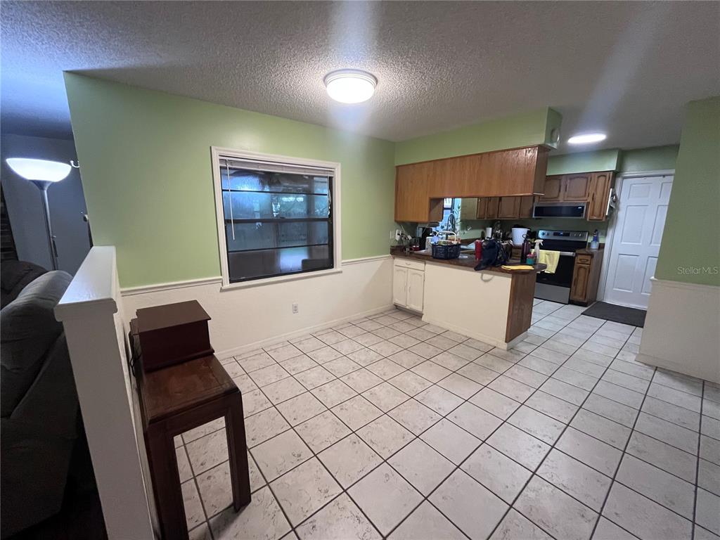 A kitchen and dining area with light green walls, white wainscoting, and tiled flooring — 2117 YORKSHIRE DRIVE, DELAND, FL