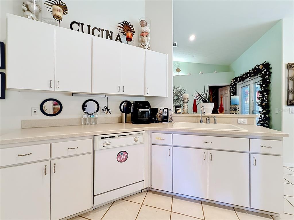 A kitchen features white cabinets, beige countertops, a white dishwasher, and a sink — 8461 N TITLEIST DRIVE, CITRUS SPRINGS, FL
