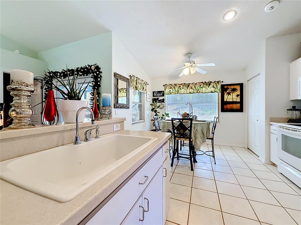 A kitchen with white cabinets and a sink overlooks a dining area with tile floors — 8461 N TITLEIST DRIVE, CITRUS SPRINGS, FL