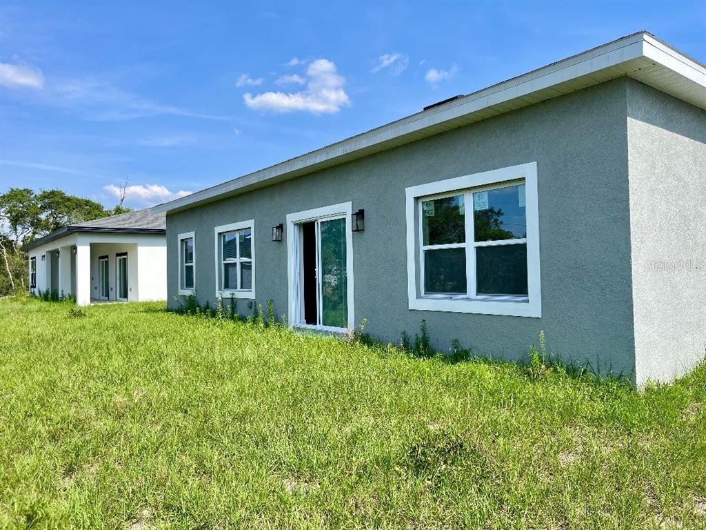The exterior of a gray stucco house features a sliding glass door and windows — 611 AMAZON PLACE, KISSIMMEE, FL
