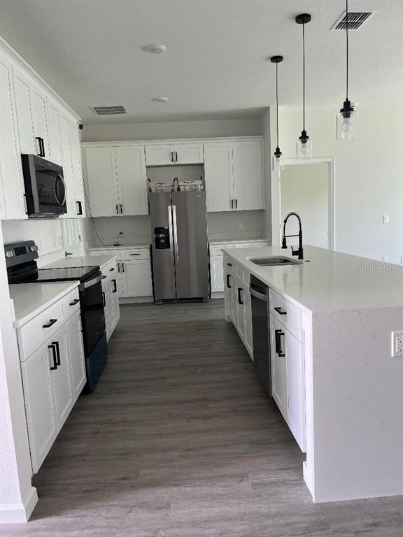 A modern kitchen features white cabinetry, stainless steel appliances, and a large quartz-topped island — 611 AMAZON PLACE, KISSIMMEE, FL