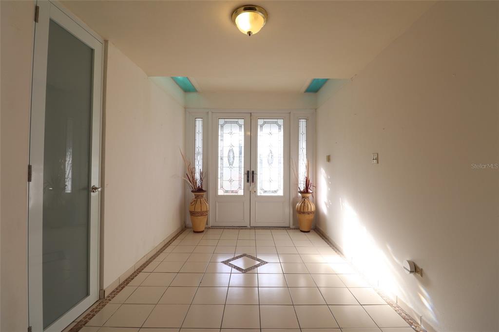 A tiled entryway features double glass-paneled doors, two decorative floor vases, and a ceiling light — 62 San Luis St. ESTANCIAS DE GRAN VISTA DEV., GURABO, PR