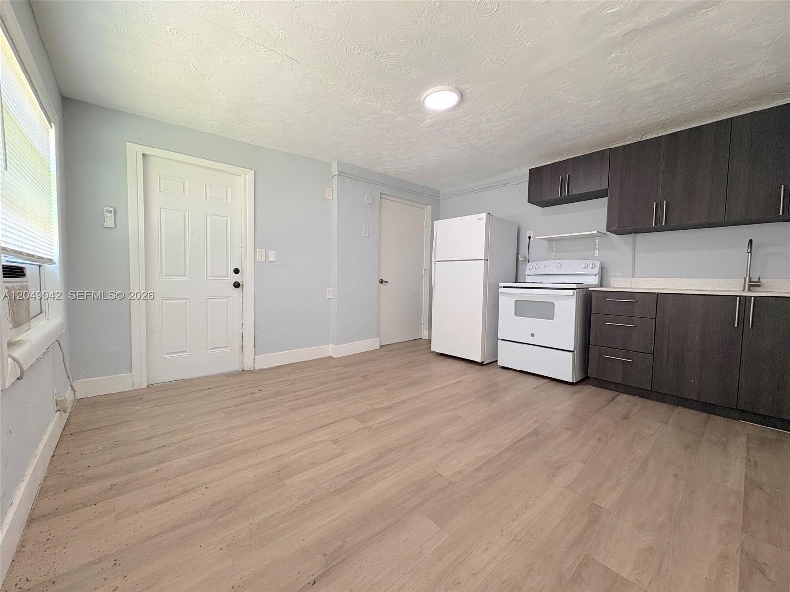 A kitchen area features light-colored wood flooring, light blue walls, and dark brown cabinetry — 1825 Mckinley St # 2, Hollywood FL 33020, HOLLYWOOD, FL