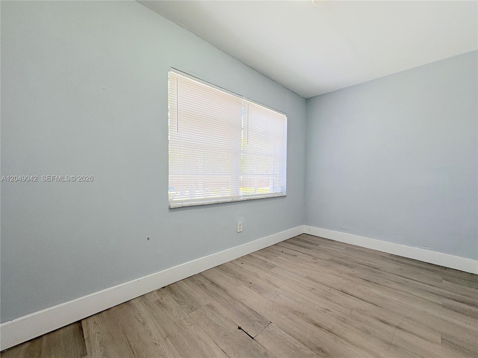 An empty room features light blue walls, white trim, and wood-look flooring — 1825 Mckinley St # 2, Hollywood FL 33020, HOLLYWOOD, FL