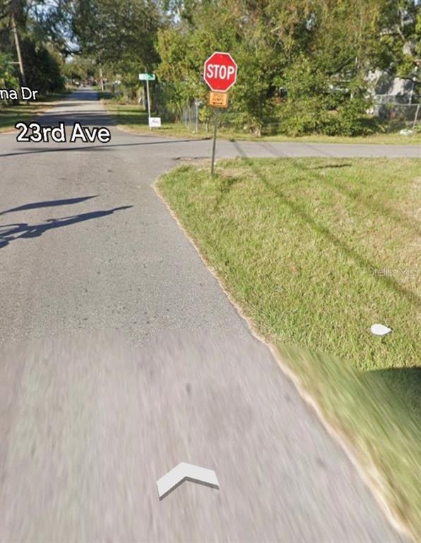 A street view shows a stop sign at an intersection with a grassy roadside — 3009 N 76TH STREET, TAMPA, FL