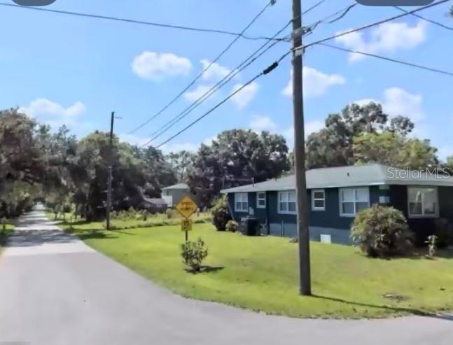 A single-story house with dark siding sits on a corner lot near a paved road — 3009 N 76TH STREET, TAMPA, FL