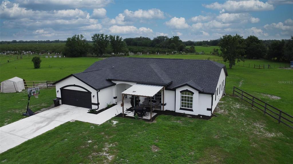 An aerial view of a white house with a black roof and attached garage — 3442 NE APPALOOSA STREET, ARCADIA, FL