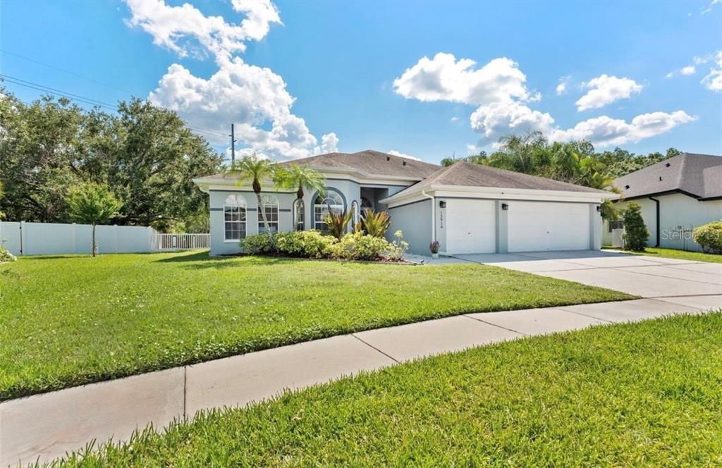 A single-story house with a two-car garage, light-colored stucco exterior, and a manicured lawn — 12910 VICKSBURG DRIVE, TAMPA, FL