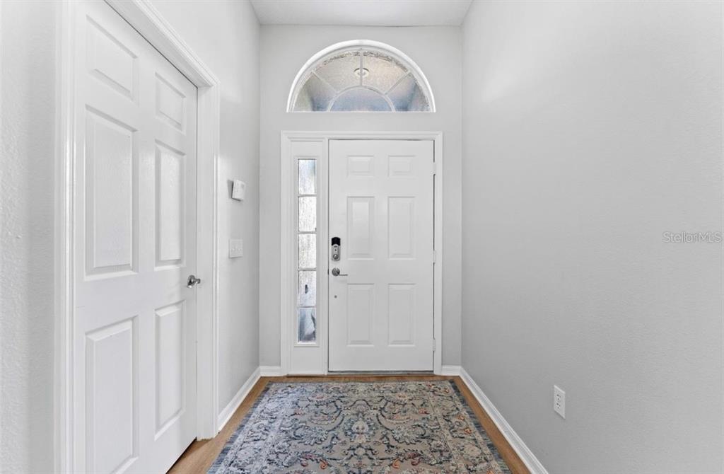 A white front door with a sidelight and arched transom window opens into a foyer — 12910 VICKSBURG DRIVE, TAMPA, FL