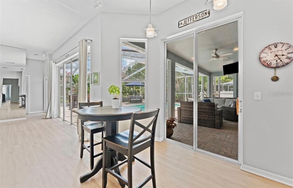 A dining area with a small round table, sliding glass doors, and a view of a pool — 12910 VICKSBURG DRIVE, TAMPA, FL