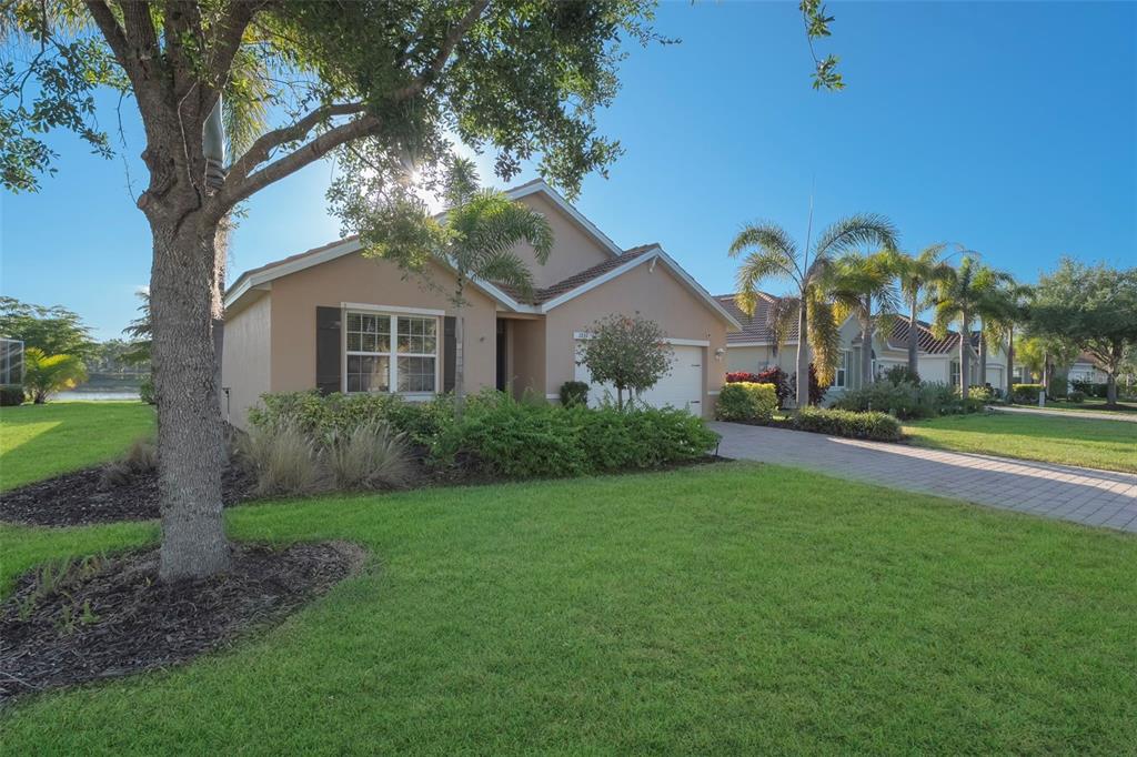 A tan single-story house with a paved driveway, palm trees, and a green lawn — 2897 APPLE BLOSSOM DRIVE, ALVA, FL