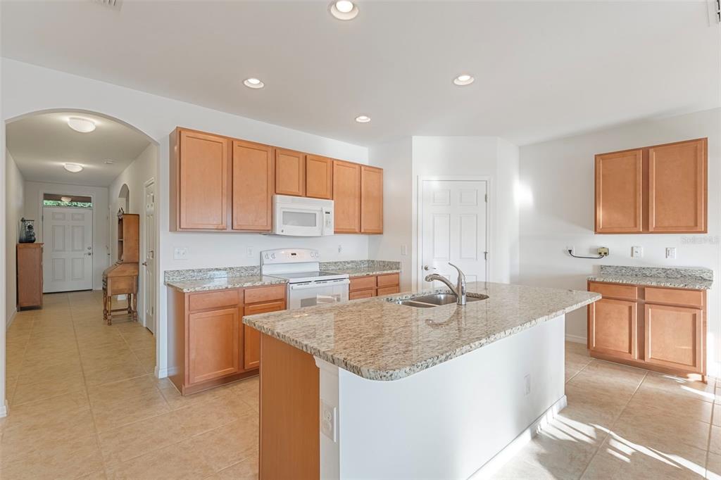 A kitchen with light wood cabinets, granite countertops, a center island, and tile flooring — 2897 APPLE BLOSSOM DRIVE, ALVA, FL