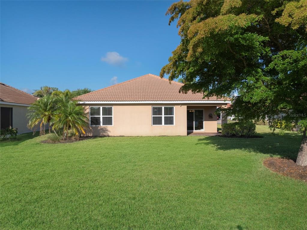 The back exterior of a single-story house with a tiled roof and a large lawn — 2897 APPLE BLOSSOM DRIVE, ALVA, FL