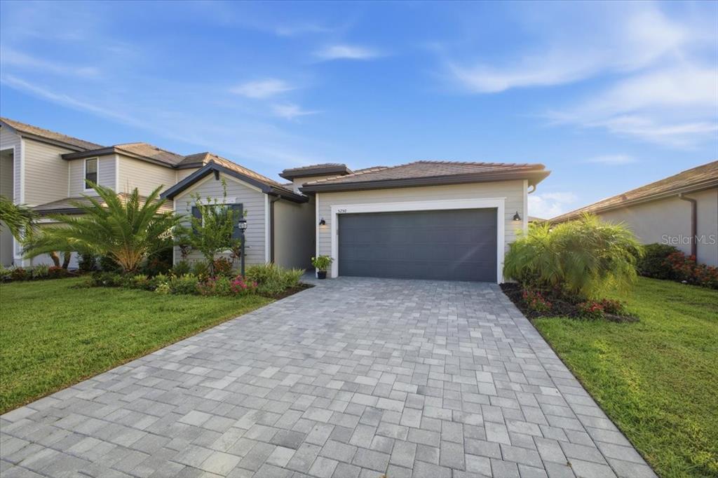 A single-story house with a gray garage, paved driveway, and landscaped front yard — 5250 CORAL REEF WAY, LAKEWOOD RANCH, FL