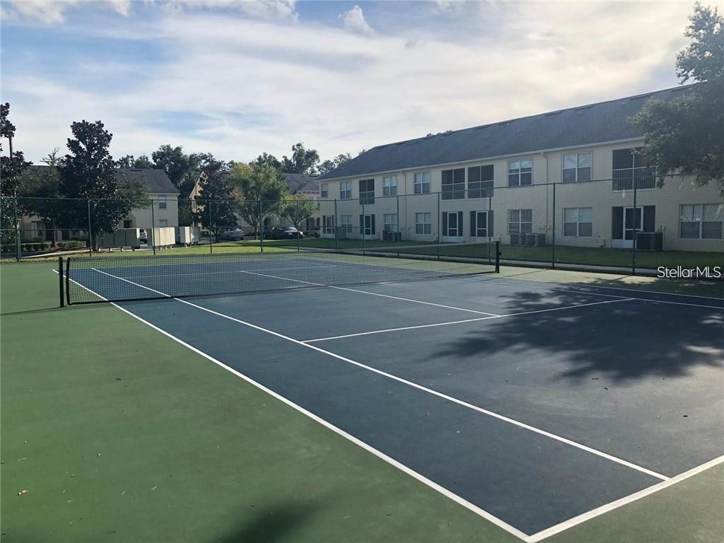 A tennis court with a net sits in front of a multi-story apartment building — 2866 CLUB CORTILE CIRCLE UNIT B, KISSIMMEE, FL