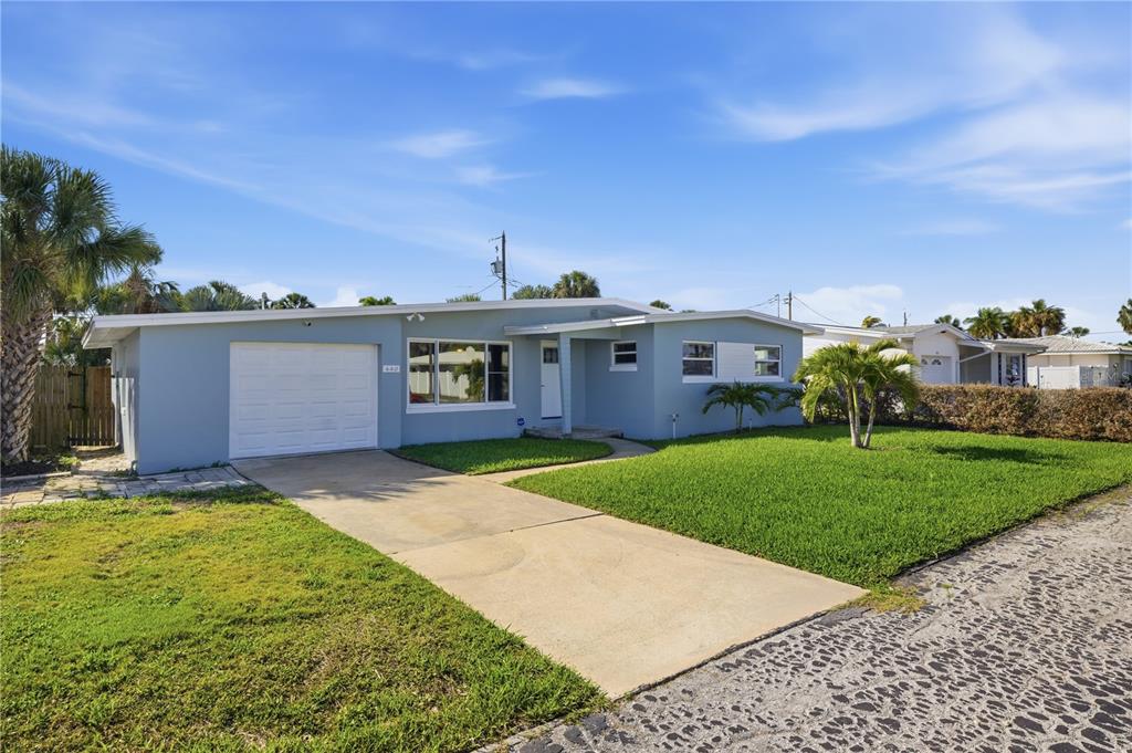 A light blue single-story house with a white garage door and a concrete driveway — 440 89TH AVENUE, ST PETE BEACH, FL
