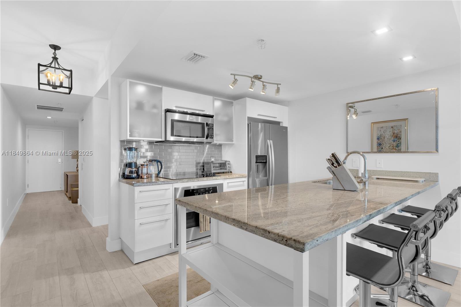 A modern kitchen features white cabinetry, granite countertops, stainless steel appliances, and a breakfast bar — 185 SW 7th St # 1901, Miami FL 33130, MIAMI, FL