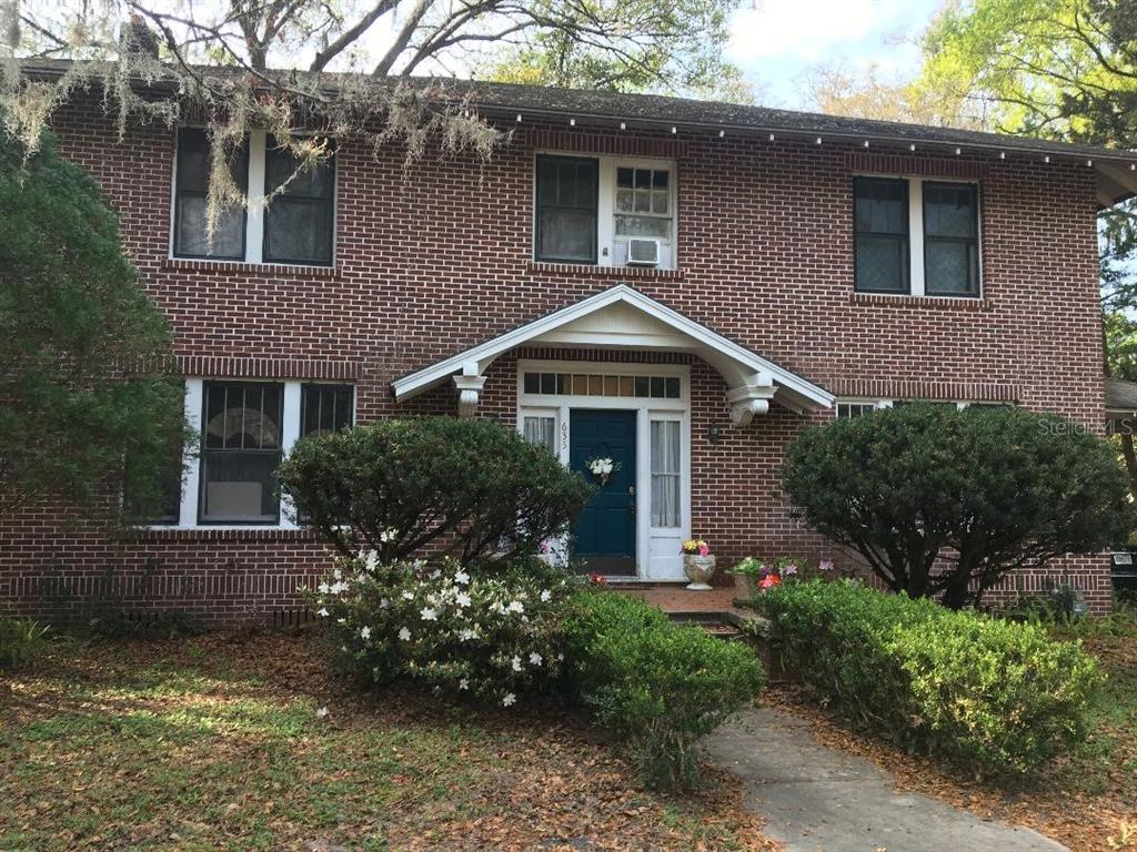 A two-story brick house features a central front door with a gabled porch roof — 635 NE 9TH AVENUE, GAINESVILLE, FL