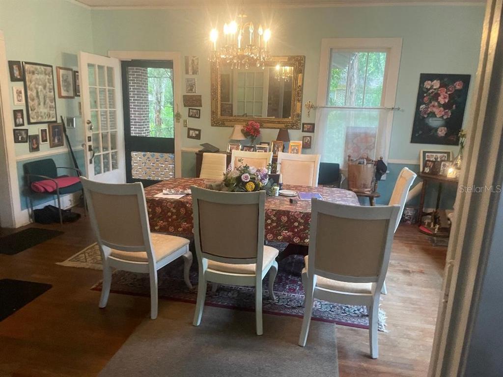 A dining room features a floral tablecloth, white chairs, a chandelier, and a large mirror — 635 NE 9TH AVENUE, GAINESVILLE, FL