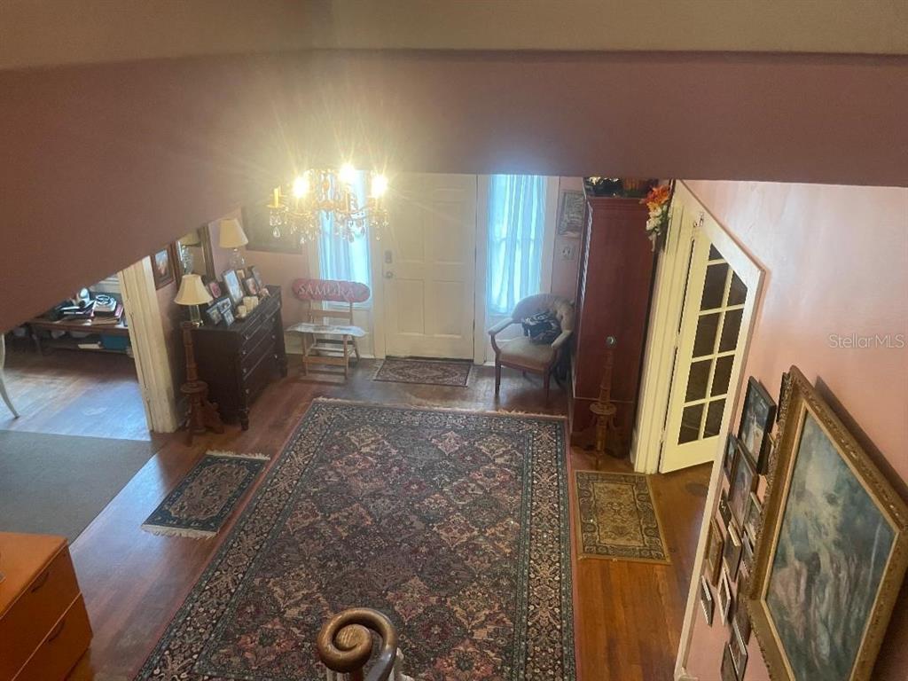 An elevated view of a foyer with hardwood floors, a large area rug, and a chandelier — 635 NE 9TH AVENUE, GAINESVILLE, FL