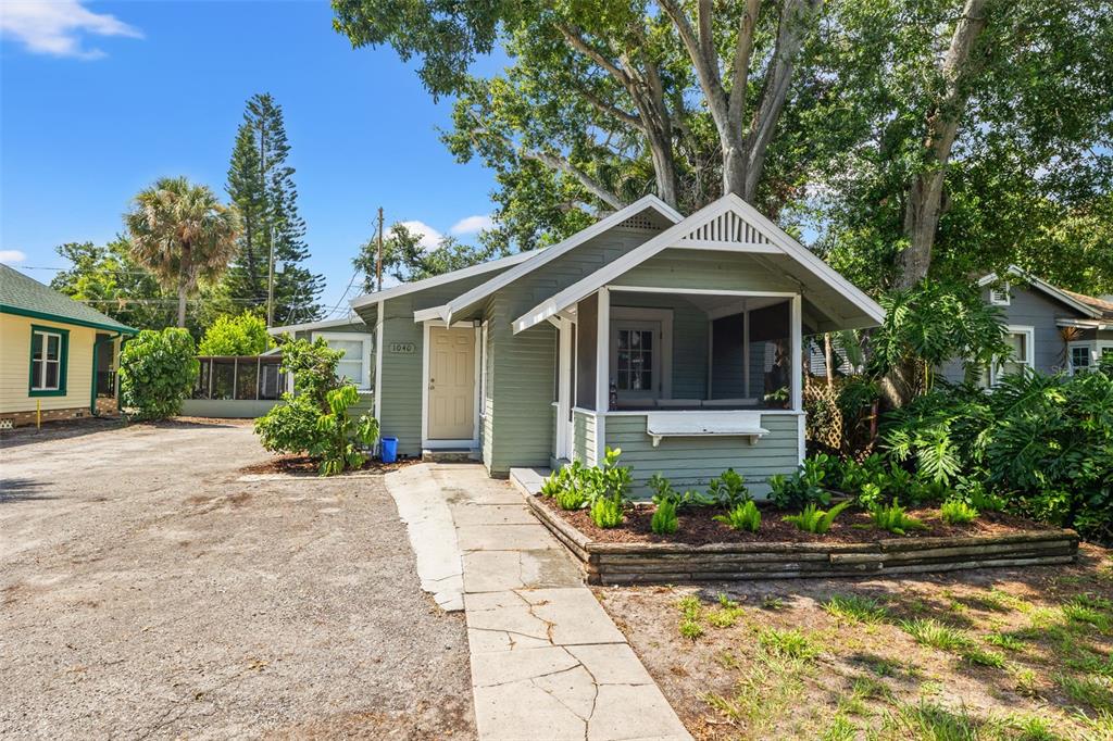 A light green, single-story house with a screened-in front porch and a gravel driveway — 1040 19TH AVENUE N, ST PETERSBURG, FL