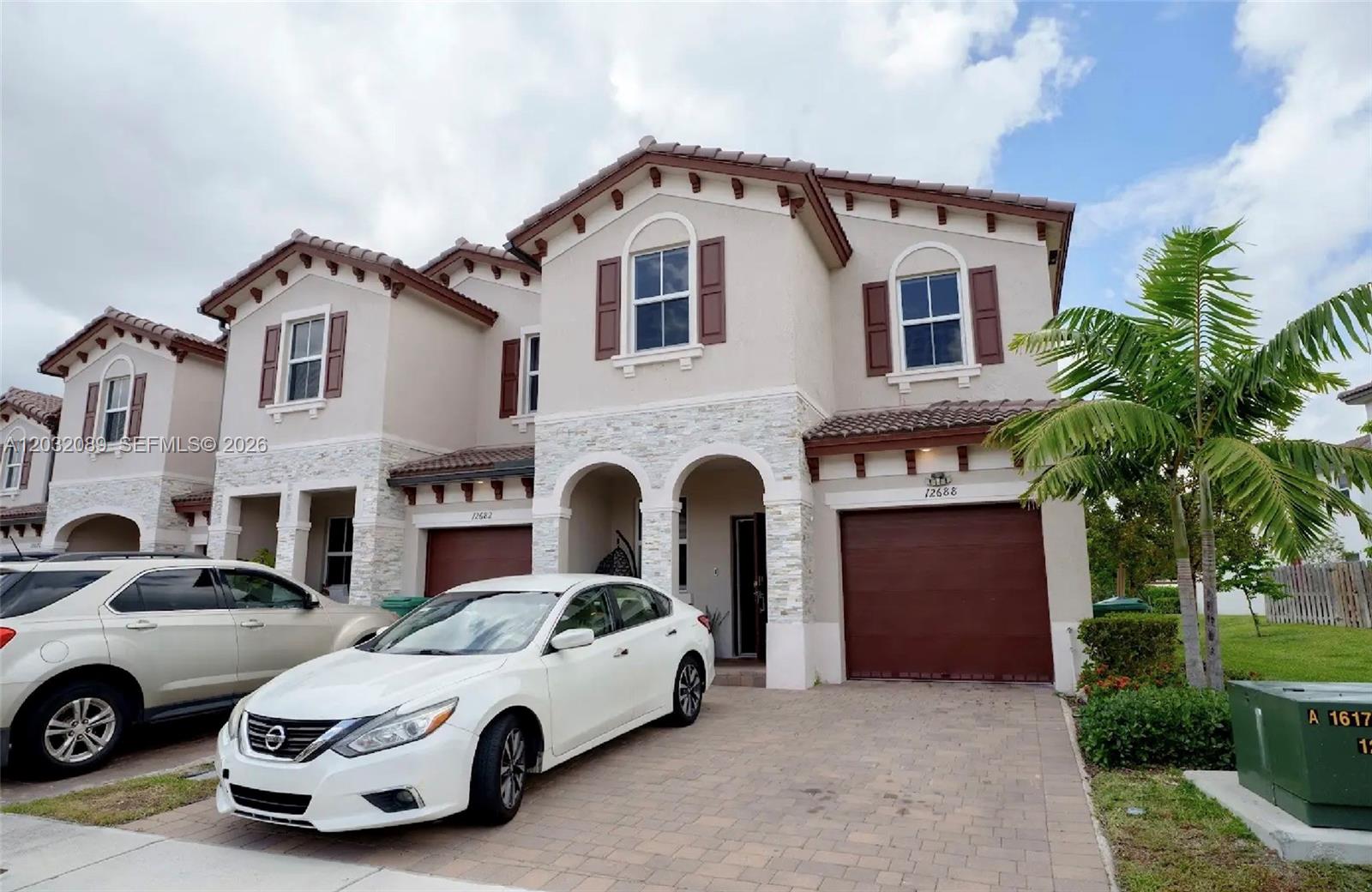 A two-story suburban townhouse with a paved driveway, two garages, and a white sedan parked — 12688 NW 23rd Pl, Miami FL 33167, MIAMI, FL