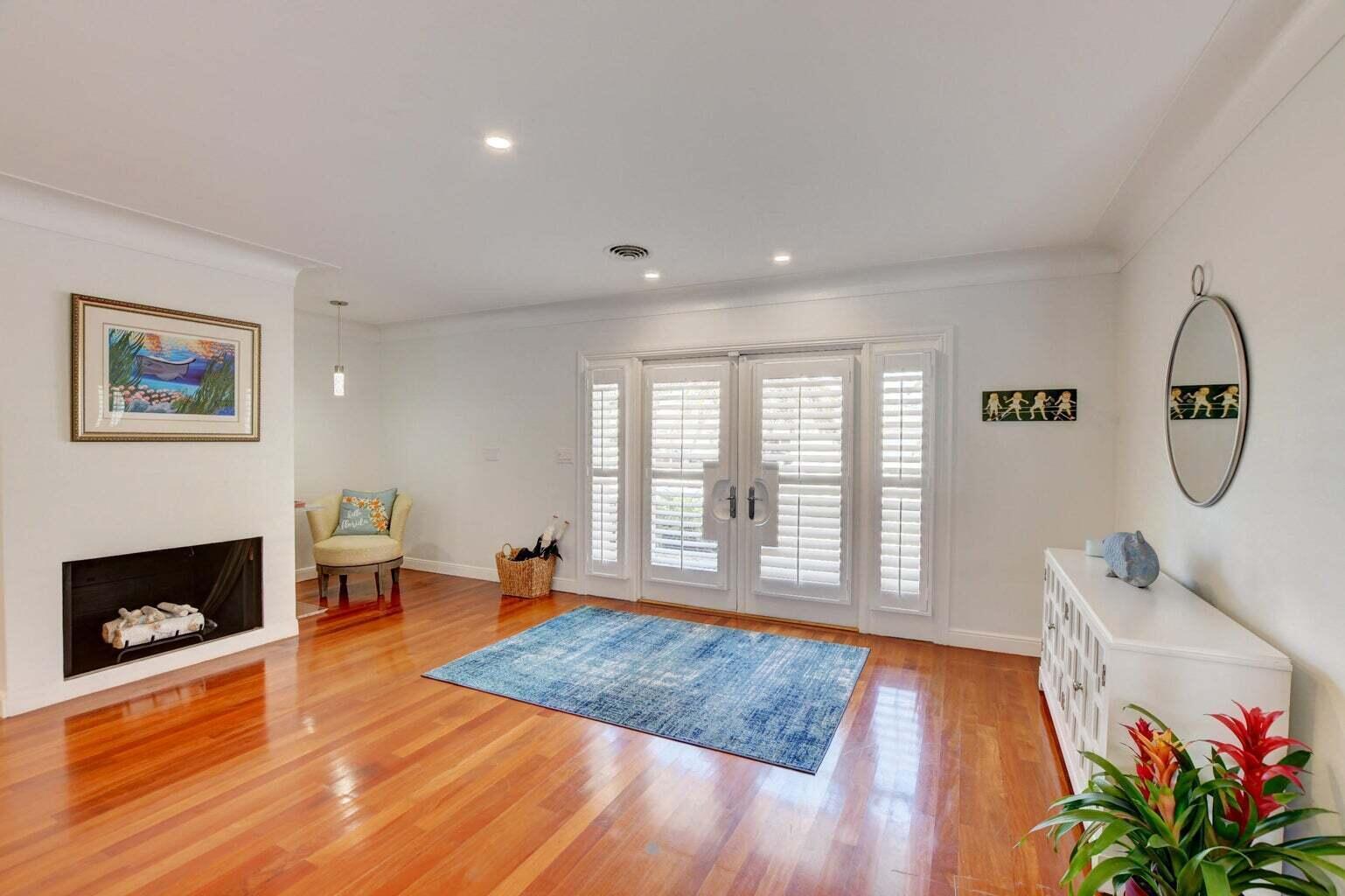A living room features hardwood floors, a fireplace, a blue area rug, and French doors — 2700 Spanish River Road, Boca Raton FL 33432, BOCA RATON, FL