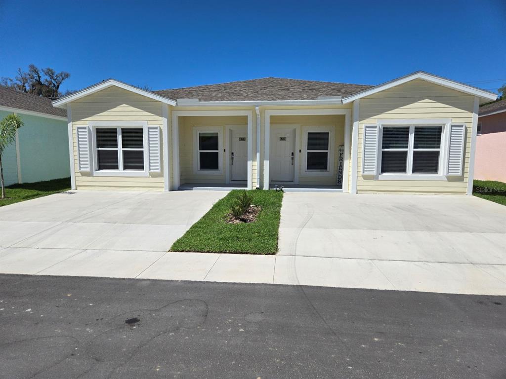 A yellow duplex with two front entrances, white shutters, and a shared concrete driveway — 7616 WASHINGTON STREET, PORT RICHEY, FL