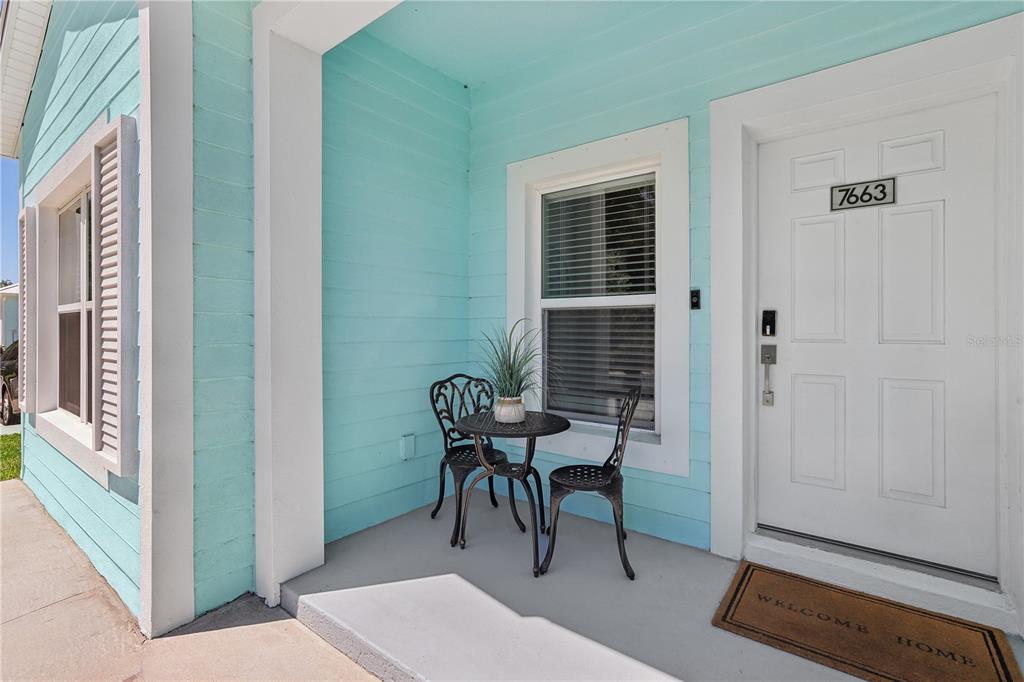 A light blue house exterior features a small front porch with a bistro set — 7616 WASHINGTON STREET, PORT RICHEY, FL