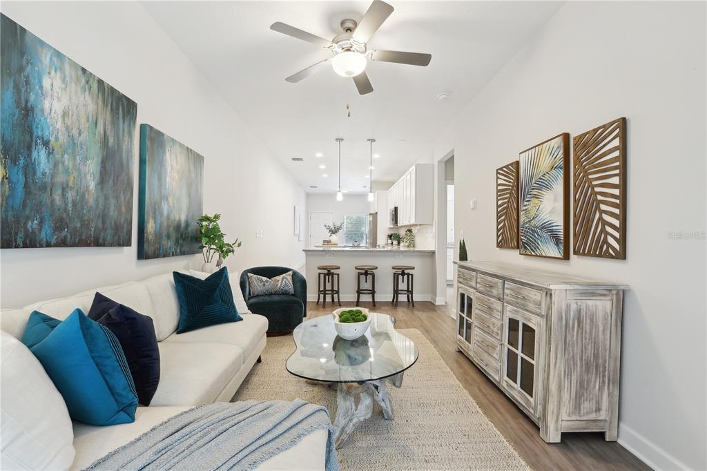 A living room with a white sofa, glass coffee table, and open kitchen in the background — 7616 WASHINGTON STREET, PORT RICHEY, FL
