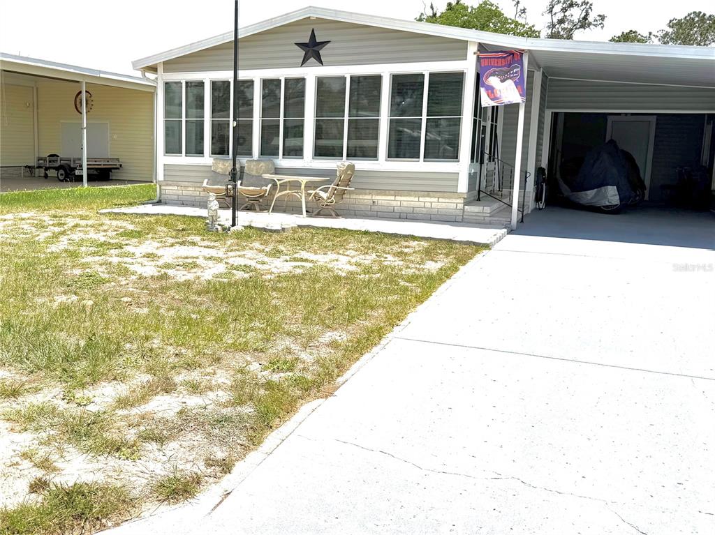 A manufactured home with a screened-in porch, a concrete driveway, and a carport — 12176 EVANTIDE AVENUE, BROOKSVILLE, FL