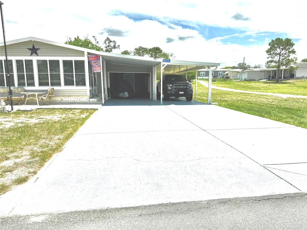 A single-story house features a concrete driveway, a carport with a truck, and a porch — 12176 EVANTIDE AVENUE, BROOKSVILLE, FL