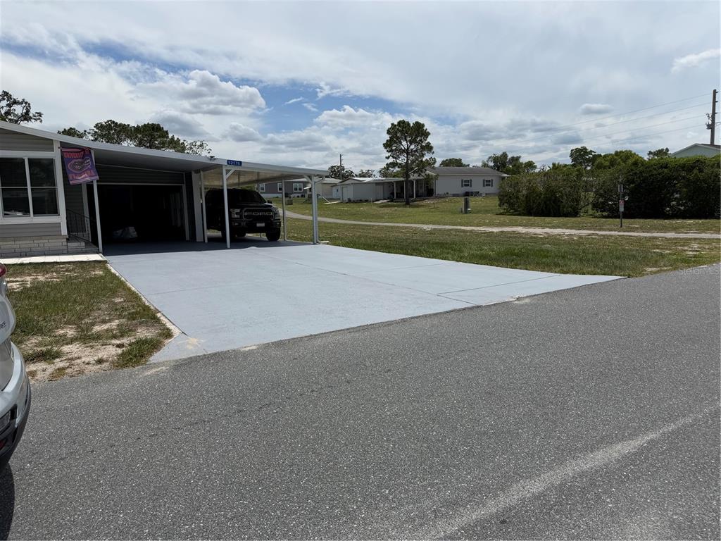 A gray painted concrete driveway and carport attached to a manufactured home — 12176 EVANTIDE AVENUE, BROOKSVILLE, FL