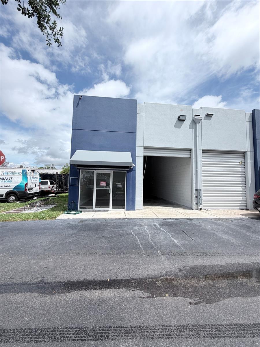 A commercial warehouse unit features a blue facade, a glass storefront, and a roll-up door — 13210 SW 132 Ave Unit 1C, Miami FL 33186, MIAMI, FL