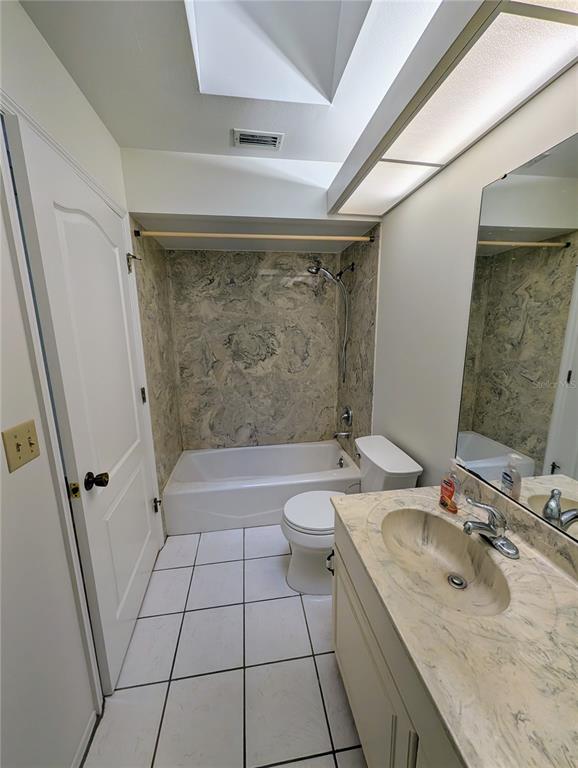 A bathroom with a white tub, a toilet, and a vanity with a marble-patterned countertop — 1315 8TH STREET W, PALMETTO, FL