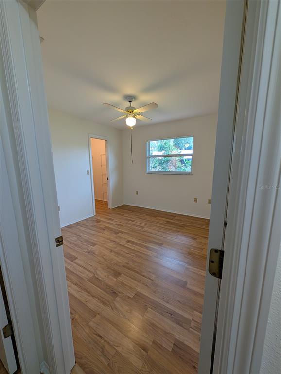 An empty bedroom features wood-look flooring, a ceiling fan, and a walk-in closet — 1315 8TH STREET W, PALMETTO, FL