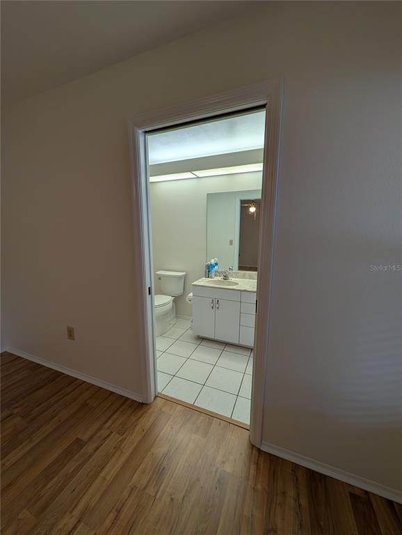 A view from a wood-floored room into a bathroom with white cabinets and tile flooring — 1315 8TH STREET W, PALMETTO, FL