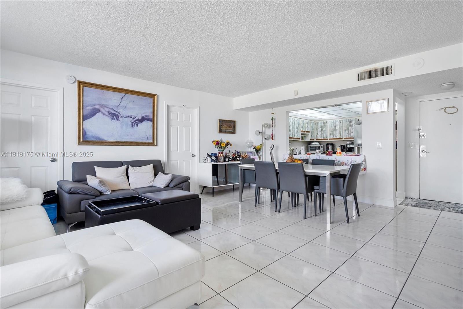 A living and dining area features white tiled floors, a grey sofa, and a dining set — 13499 Biscayne Blvd # 406, North Miami FL 33181, NORTH MIAMI, FL