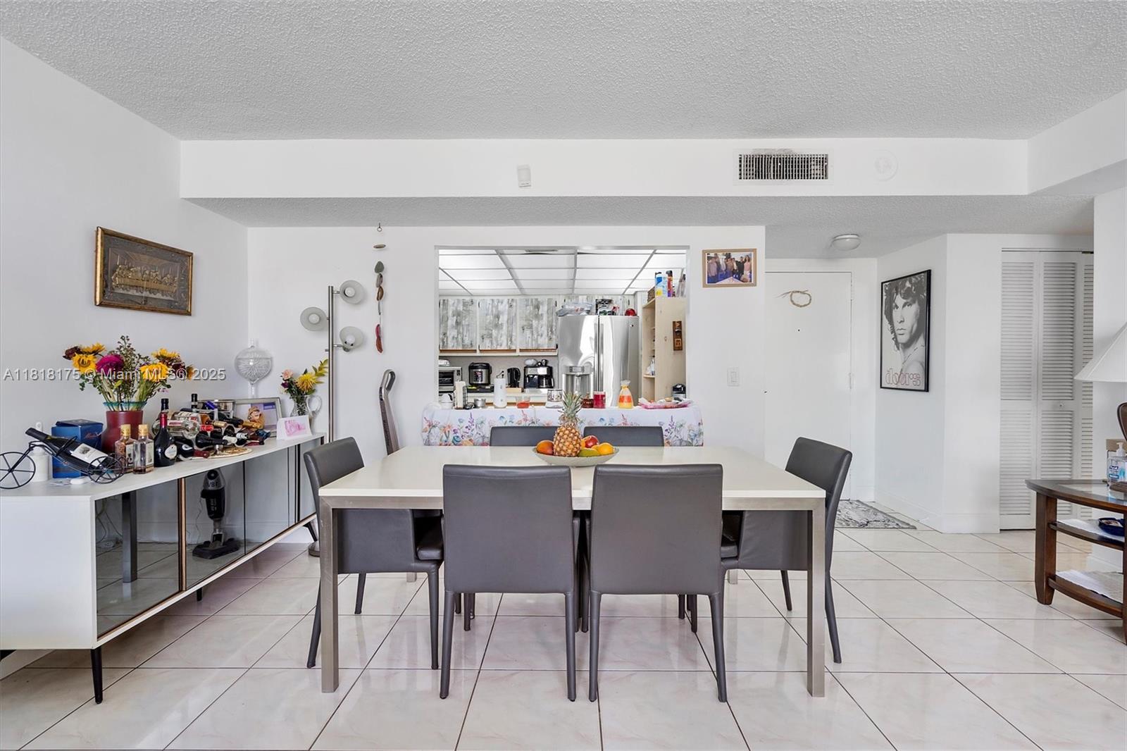 A dining room with a white table, six gray chairs, and a kitchen pass-through window — 13499 Biscayne Blvd # 406, North Miami FL 33181, NORTH MIAMI, FL