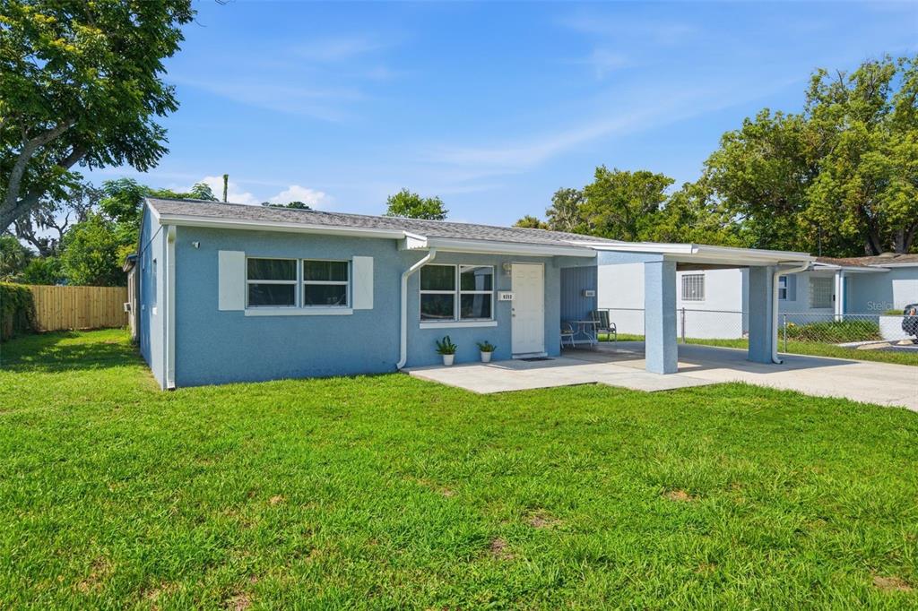 A light blue single-story house with a white front door and an attached carport — 6252 MASSACHUSETTS AVENUE, NEW PORT RICHEY, FL