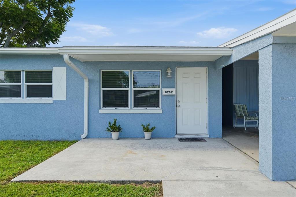 The exterior of a light blue house features a concrete porch, front door, and windows — 6252 MASSACHUSETTS AVENUE, NEW PORT RICHEY, FL