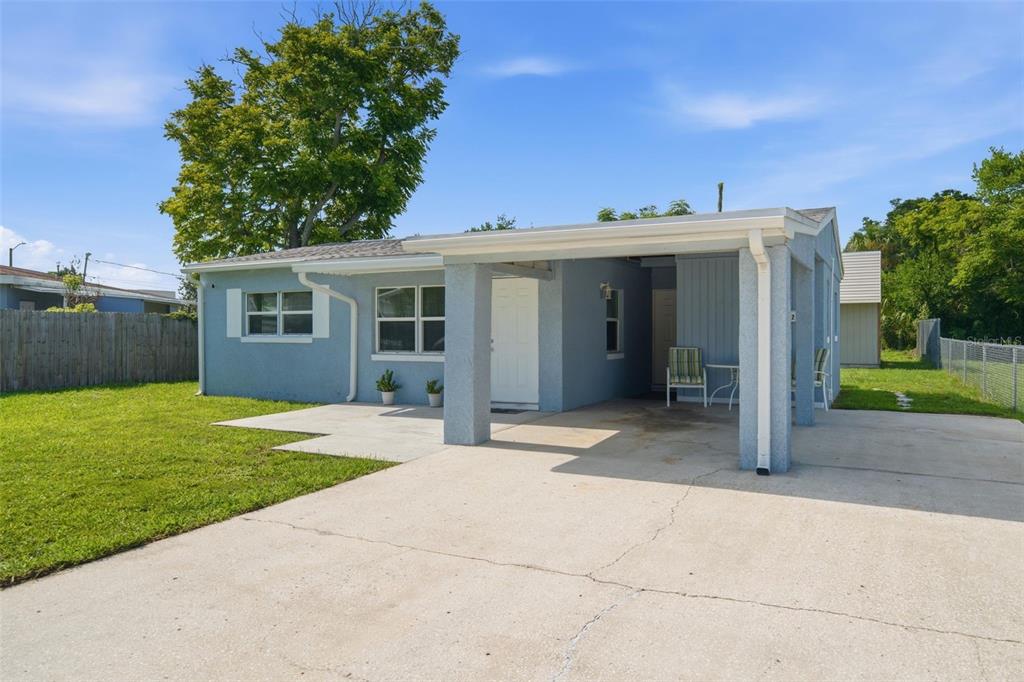A light blue single-story house features a concrete driveway, a covered carport, and a lawn — 6252 MASSACHUSETTS AVENUE, NEW PORT RICHEY, FL